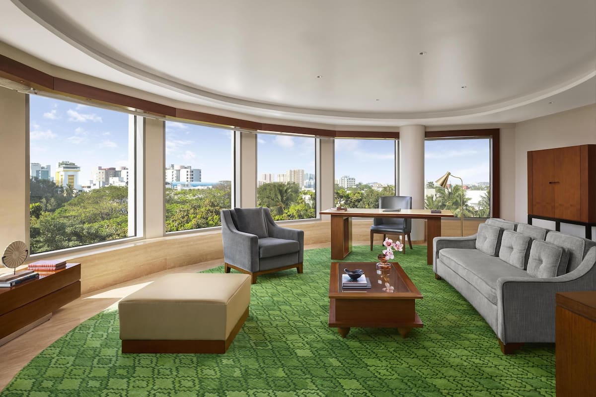 A spacious living room with a curved ceiling, large windows offering a city view, a sofa, a coffee table, and a chair.