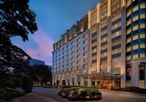 Un hotel de varios pisos con fachada moderna, amplios ventanales y un jardín bien cuidado al frente.