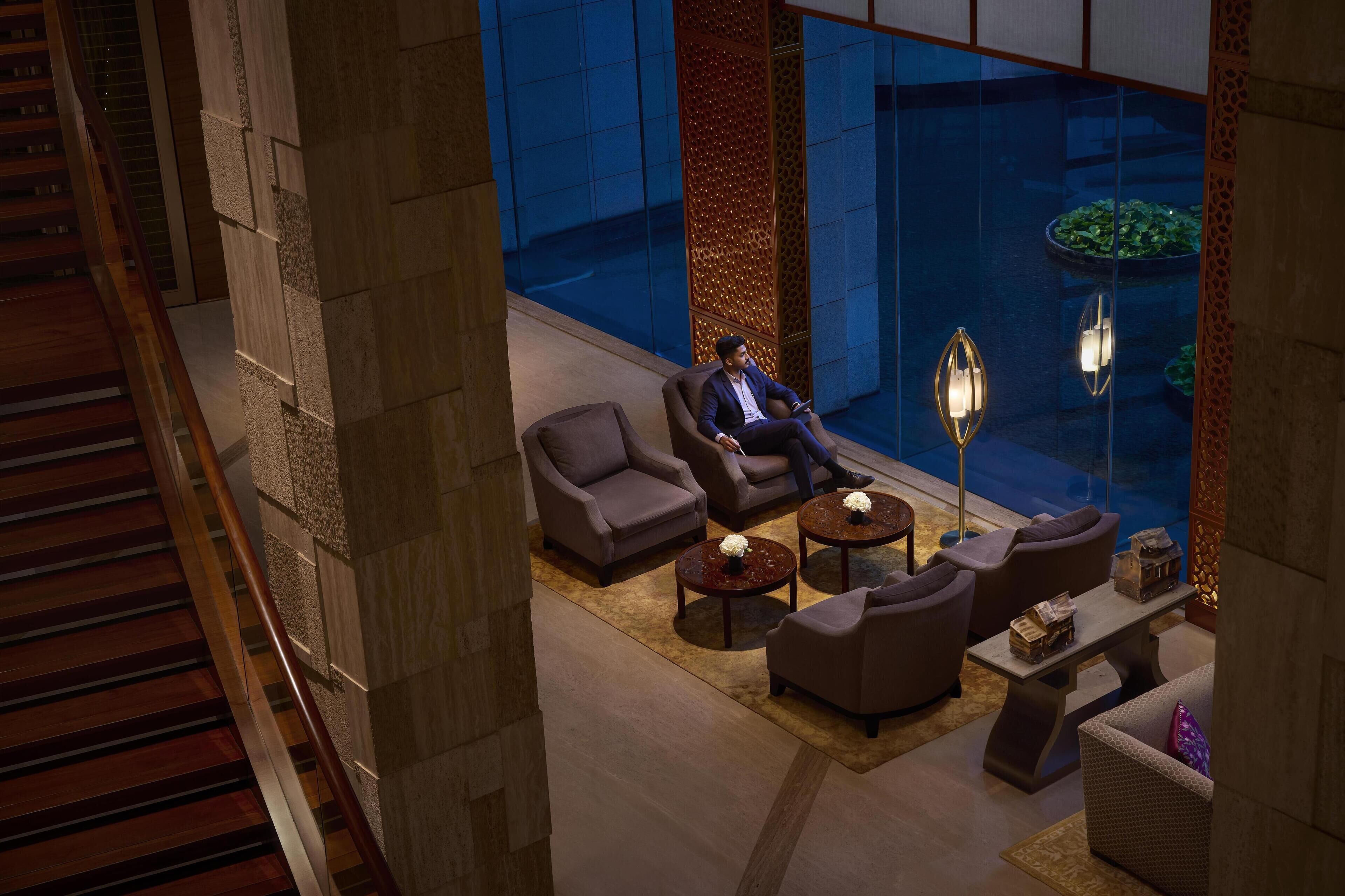 A modern indoor setting with a pool, seating area, and a person sitting on a couch.