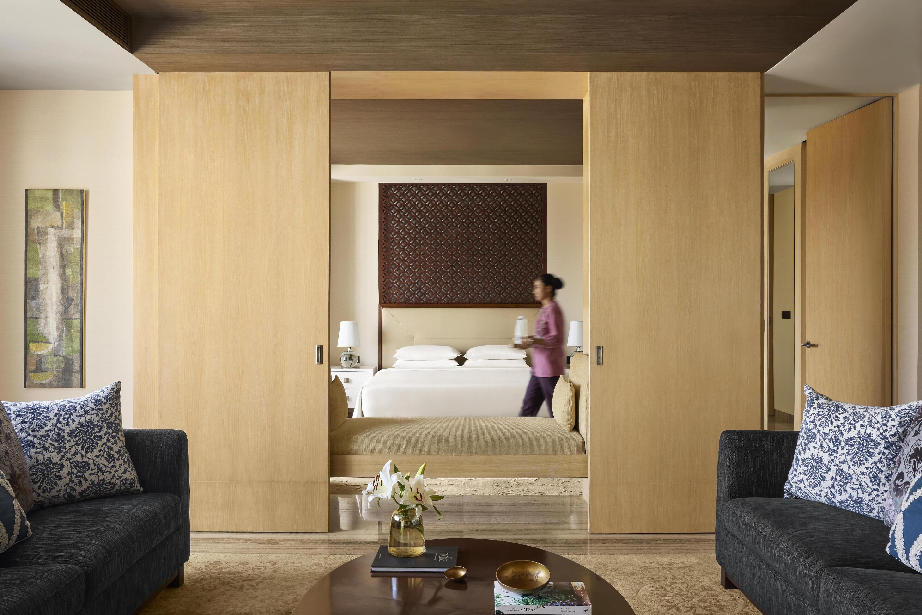 Una habitación de hotel moderna con una cama grande, una mesita de noche y una mesa de centro con un libro y un florero.