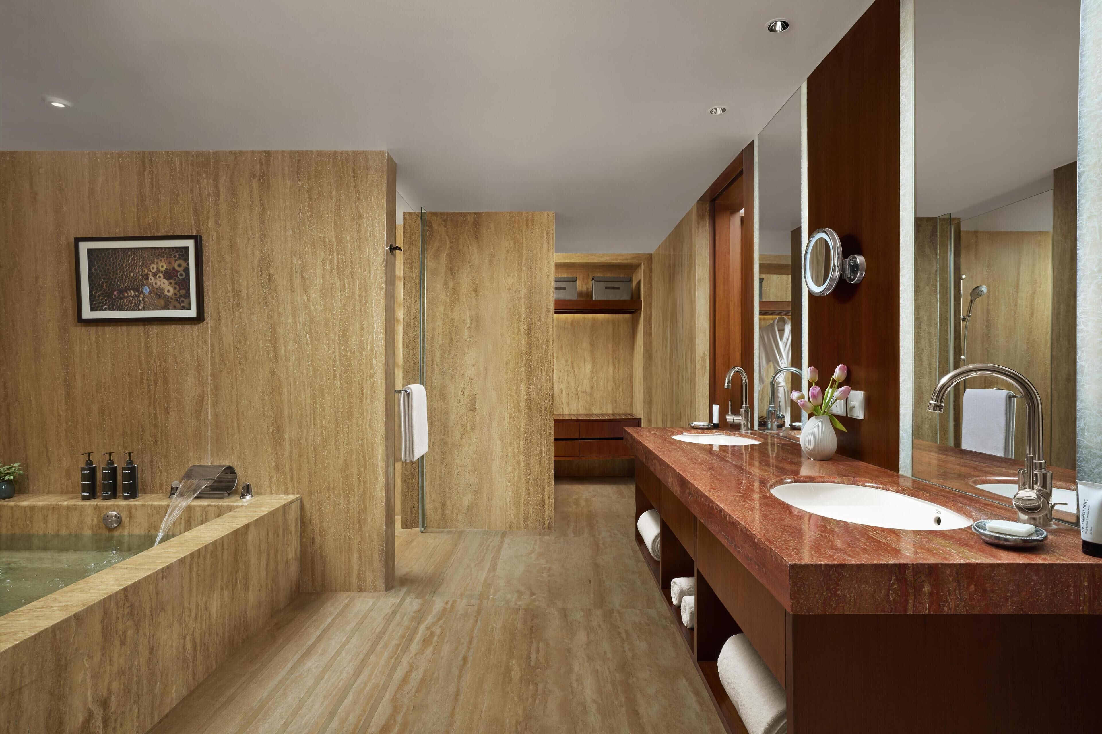 Un baño moderno con un espejo grande, dos lavamanos, una bañera y una ducha.