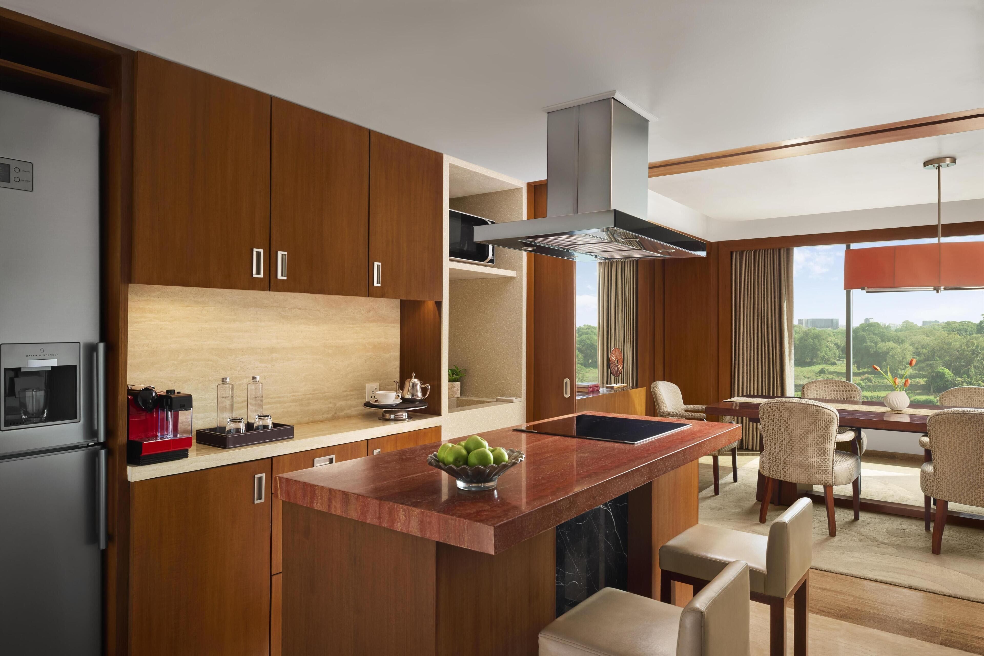 A modern kitchen with wooden cabinets, a central island, and a dining area with chairs and a table.