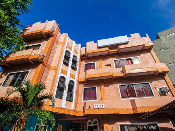 A multi-story building with a prominent 'OYO' sign, featuring a modern architectural style with a mix of brick and stucco textures. - La Maria Pension And Tourist Inn Hotel (Mandaue)