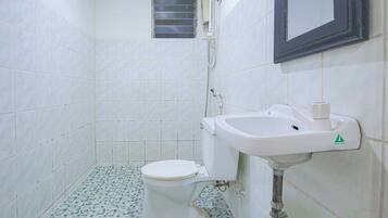 A small, tiled bathroom with a toilet, sink, and a window.