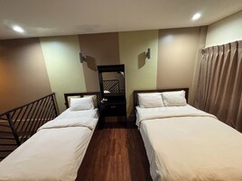 Habitación de hotel con dos camas individuales, una mesita de noche, un espejo y suelo de madera.