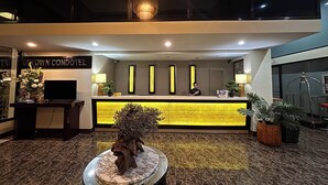 A hotel reception desk with a modern design, a reception area, and a decorative wooden sculpture. - Noorway Hotel and Residences (Cagayan de Oro)