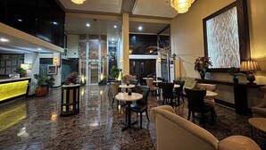 A hotel lobby with a reception desk, seating area, and a staircase leading to an upper floor. - Noorway Hotel and Residences (Cagayan de Oro)
