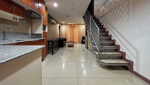 A modern kitchen with granite countertops, wooden cabinets, and a stainless steel staircase. - Noorway Hotel and Residences (Cagayan de Oro)