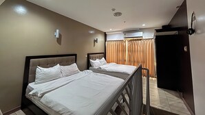 A hotel room with two beds, a ceiling light, an air conditioning unit, and a door. - Noorway Hotel and Residences (Cagayan de Oro)