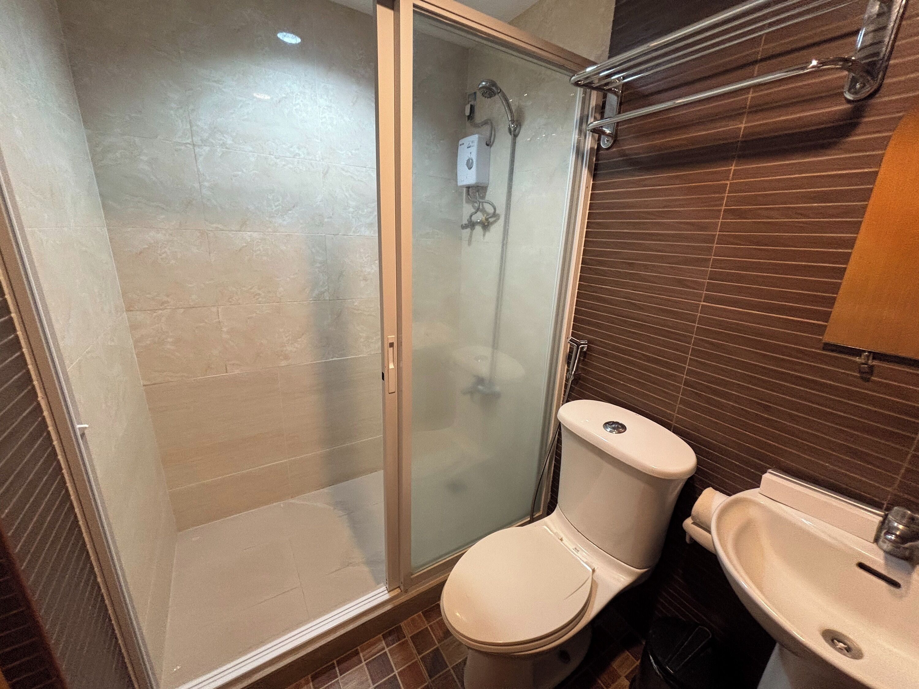 A bathroom with a glass-enclosed shower, a toilet, and a sink.