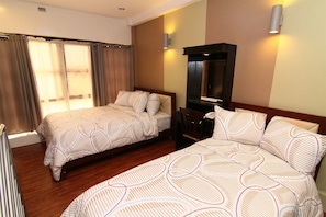 Quarto de hotel com duas camas, piso de madeira, espelho e televisão.