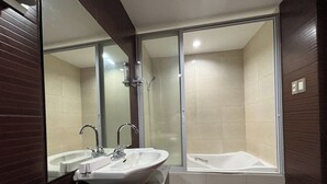 A modern bathroom with a large mirror, two sinks, a bathtub, and tiled walls. - Noorway Hotel and Residences (Cagayan de Oro)