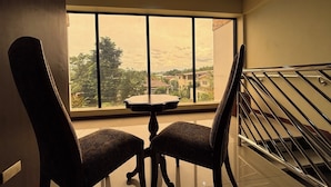 A room with a large window, two chairs, a small table, and a staircase. - Noorway Hotel and Residences (Cagayan de Oro)