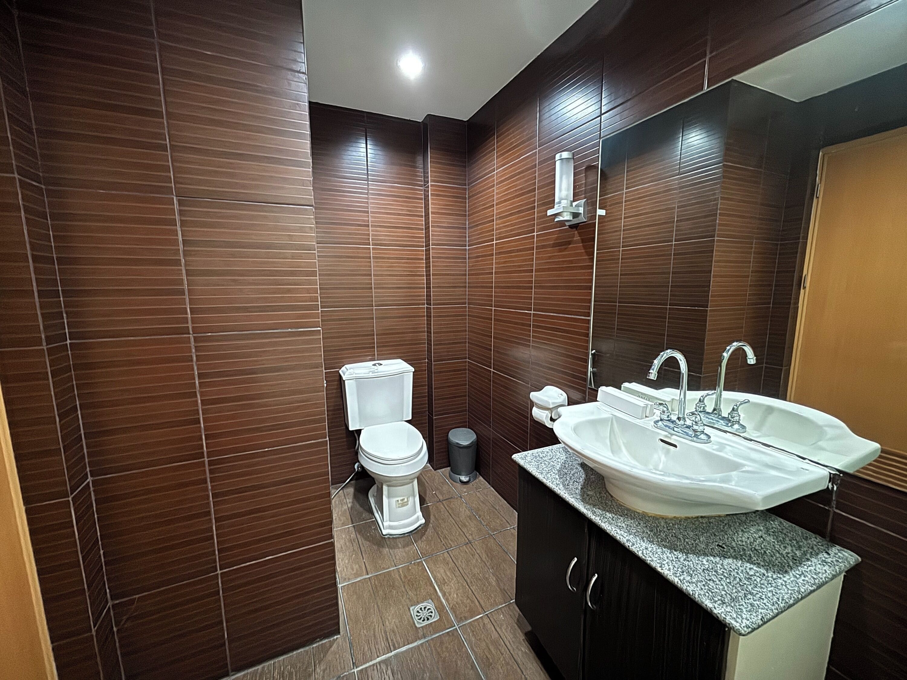 Uma casa de banho moderna com sanita, lavatório e espelho.