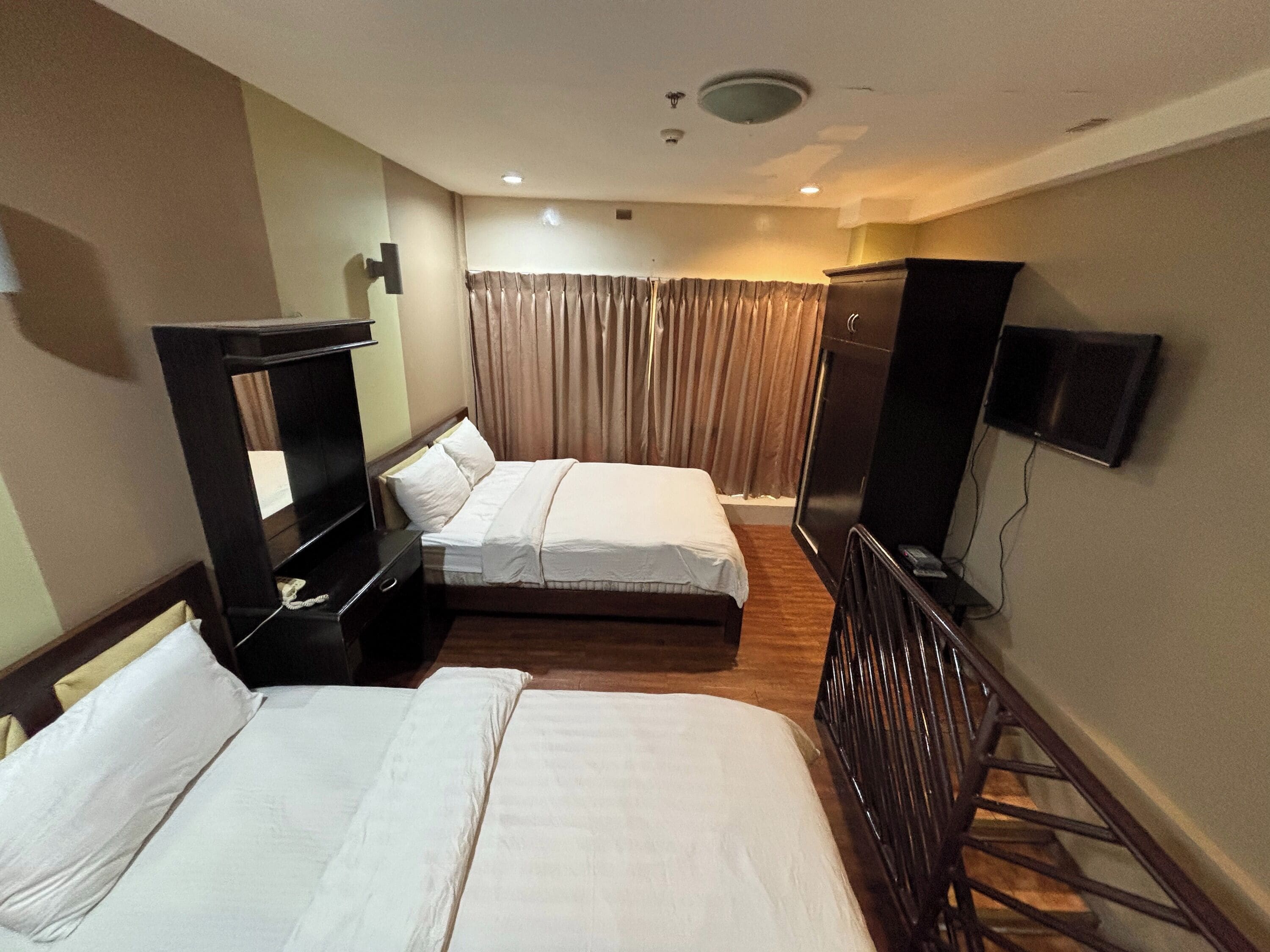 A hotel room with two beds, a TV, a desk, and a wardrobe.