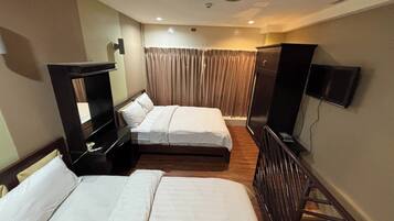 A hotel room with two beds, a TV, a desk, and a wardrobe.
