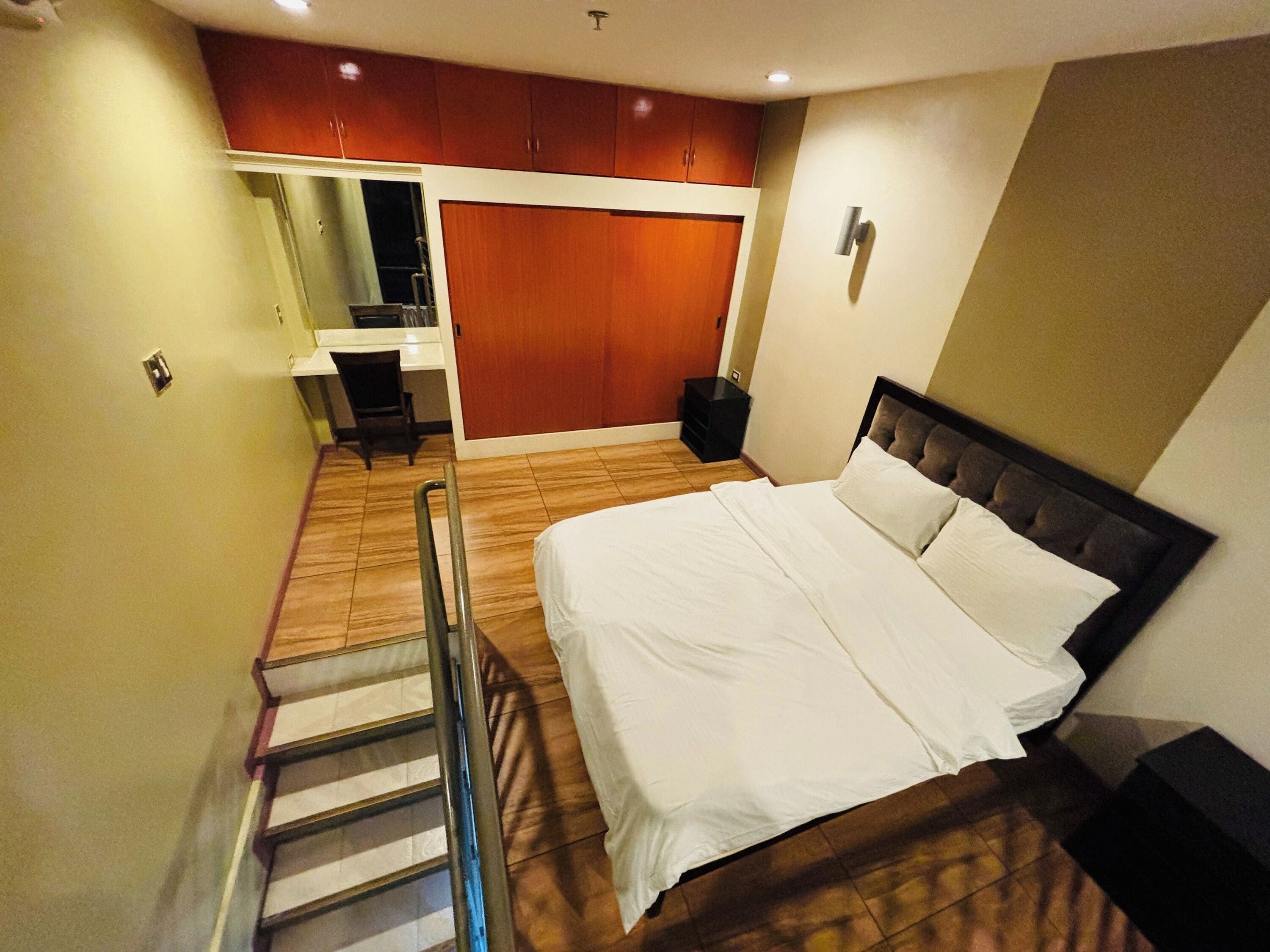 Een slaapkamer met een bed, een bureau en een stoel.