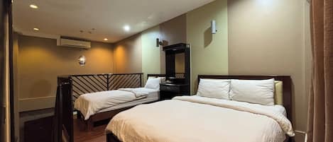 A hotel room with two beds, a mirror, a desk, and a ceiling light.