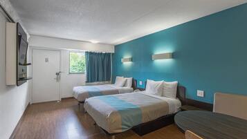Une chambre d’hôtel avec deux lits, un bureau et une fenêtre avec des rideaux.
