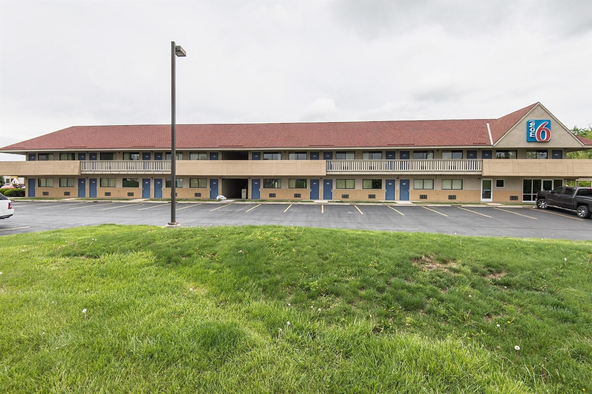 Ein Motel mit rotem Dach, mehreren Zimmern und einem Parkplatz.