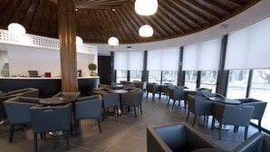 Un ristorante moderno con soffitto in legno, ampie finestre e arredamento contemporaneo.