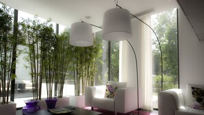 Un soggiorno moderno con un divano bianco, un tavolino da caffè e una lampada da terra. Grandi finestre offrono vista su alberi.