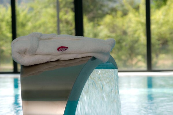 A white towel on a pool edge with a clear view of a pool and greenery in the background. - Primavera Perfume Hotel (Chaves)