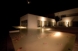 A modern building with a reflective pool and a tree. - Primavera Perfume Hotel (Chaves)
