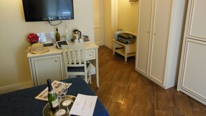 A hotel room with a desk, a television, a minibar, and a wardrobe. - Locanda Colosseo (Rome)