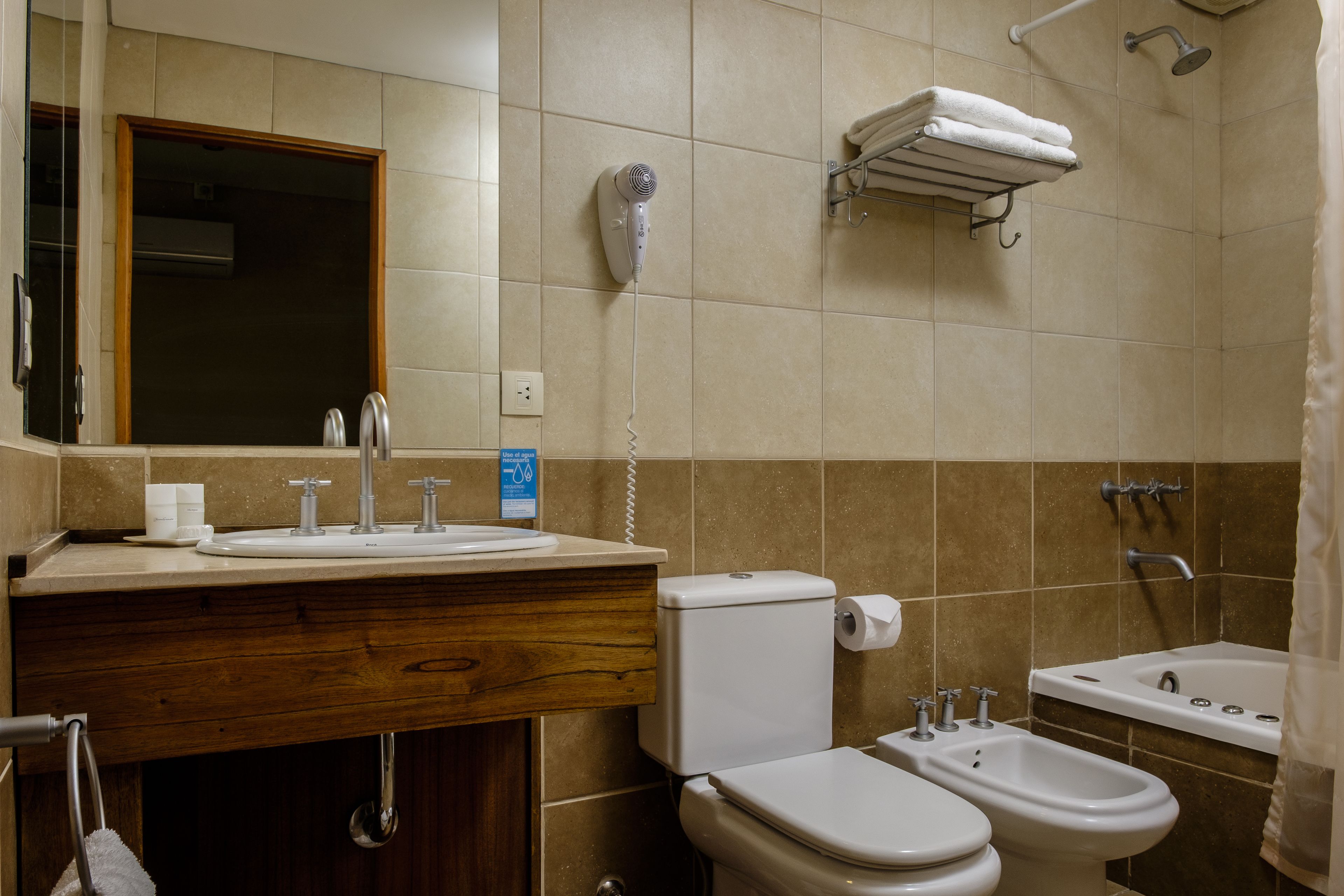 Un baño con lavabo, inodoro, bidé y secador de pelo sujeto a la pared.