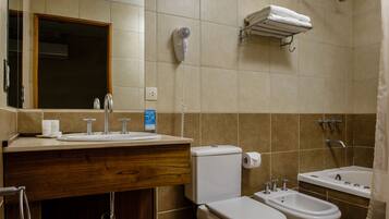 Un baño con lavabo, inodoro, bidé y secador de pelo sujeto a la pared.