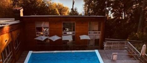 Una piscina rectangular con un borde de madera que la rodea.
