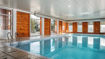 An indoor swimming pool with wooden walls and large windows.