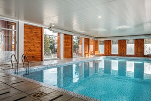 An indoor swimming pool with wooden walls and large windows.