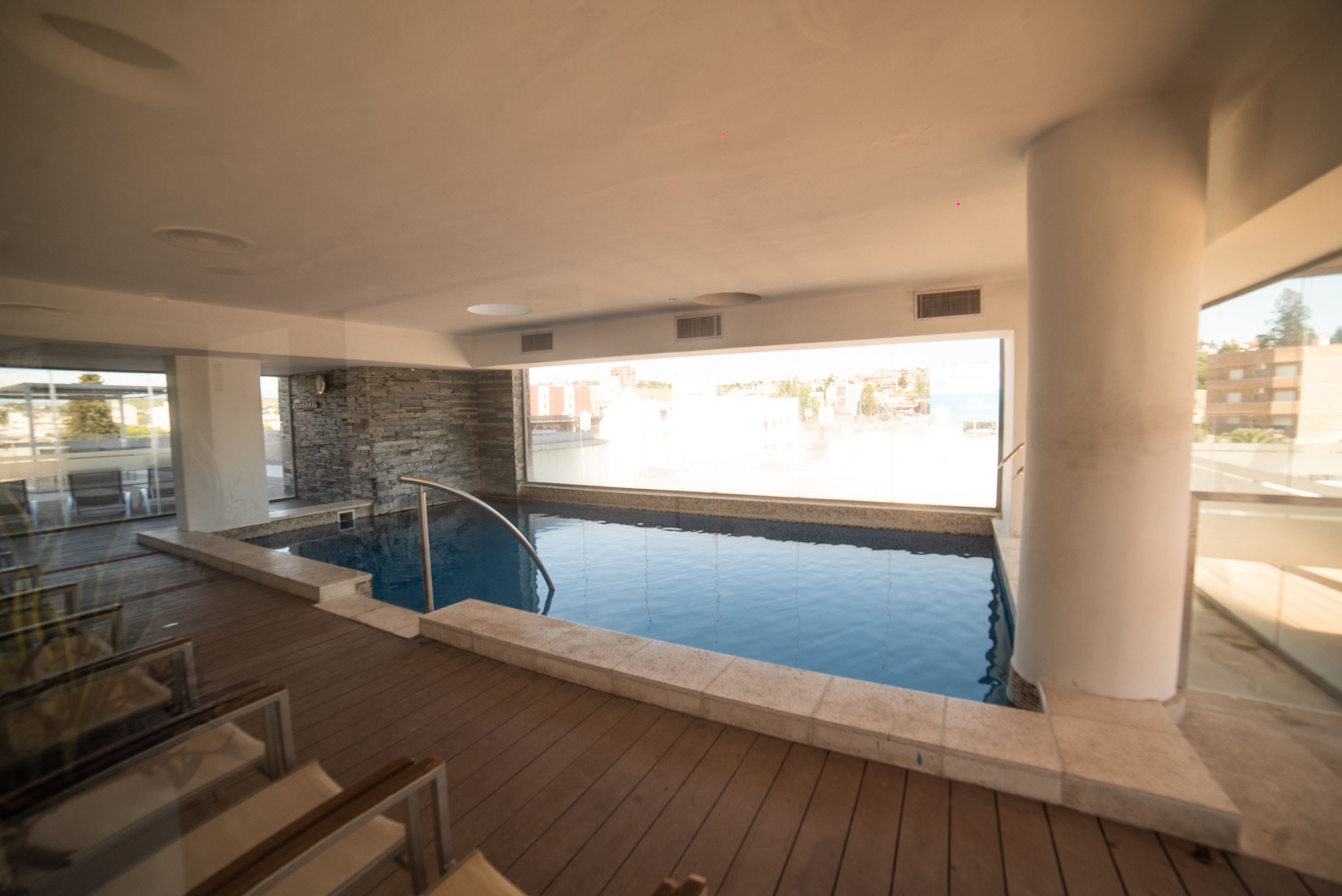 A swimming pool with a stone wall and a wooden deck.