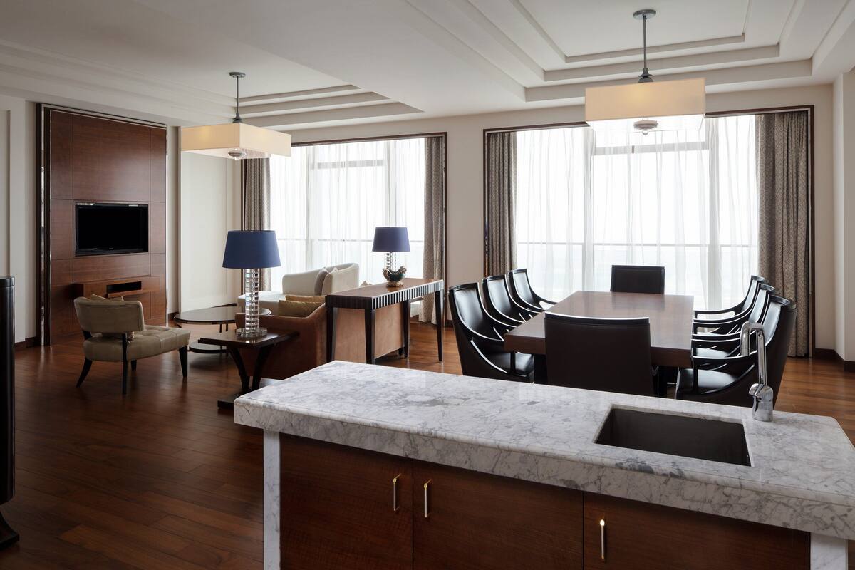 Ein modernes Hotelzimmer mit Essbereich, Fernseher und einer Marmorkücheleinheit.