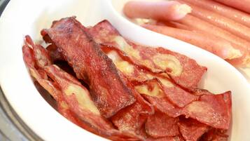 A bowl containing bacon strips and sausage links.