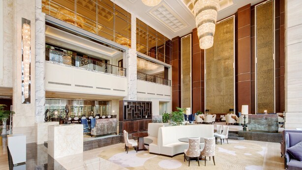 A spacious lobby with a high ceiling, marble flooring, and a central seating area with sofas and chairs. - Sheraton Qingdao Jiaozhou Hotel (Qingdao)