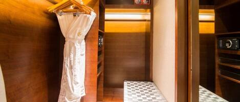 A narrow, wooden-finished bathroom with a towel rack, a small step, and a microwave.