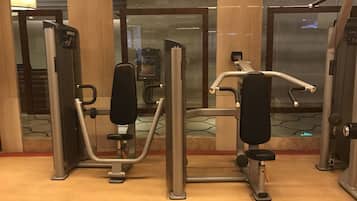 A fitness area with exercise machines, a mirror, and a glass door.