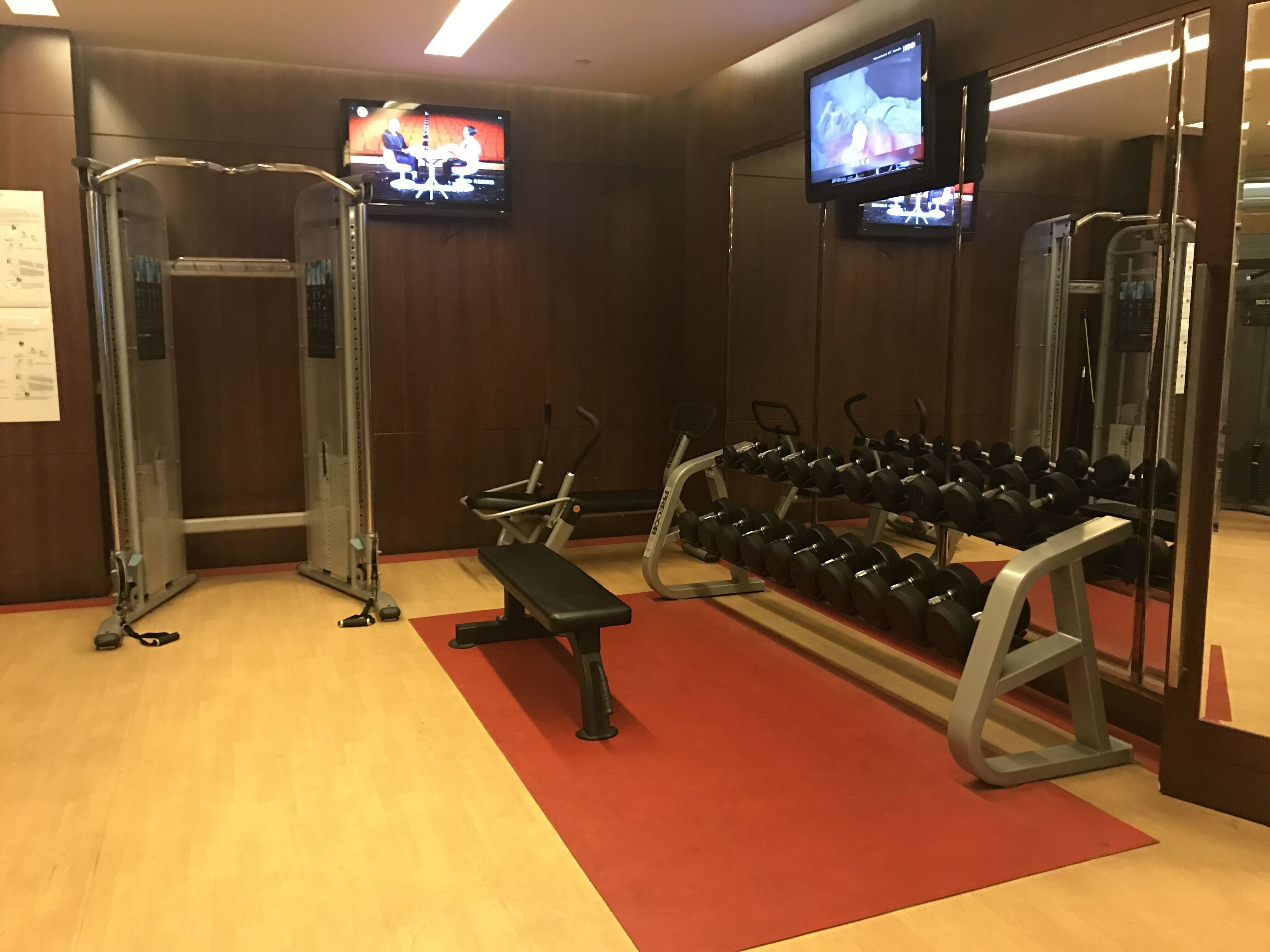 A gym with weightlifting equipment, benches, and dumbbells.