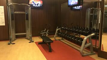 A gym with weightlifting equipment, benches, and dumbbells.