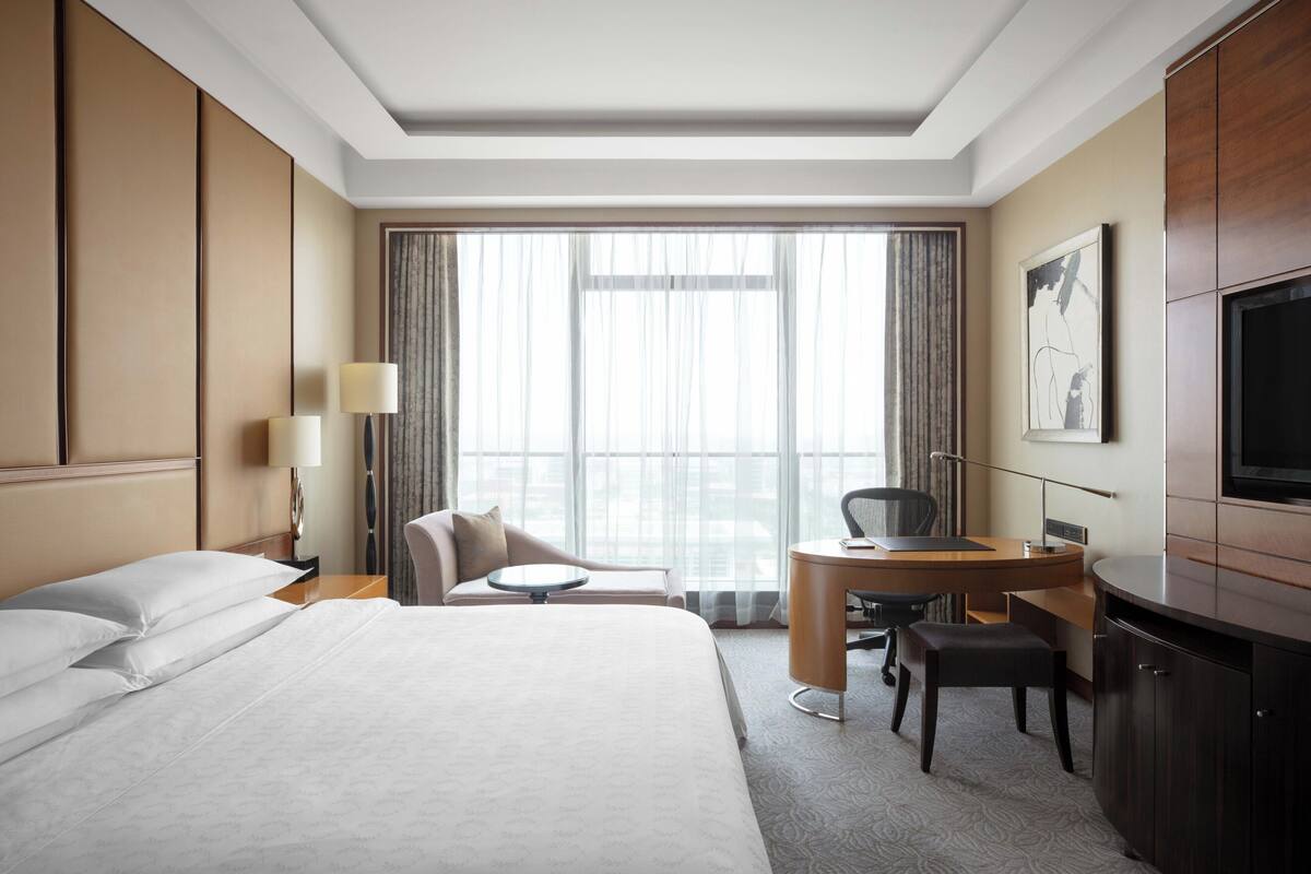 Ein Hotelzimmer mit Bett, Schreibtisch, Stuhl und Fernseher.
