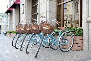 A row of bicycles with baskets parked in front of a building.