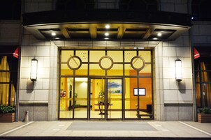 A hotel entrance with a glass facade, a central door, and two side entrances.