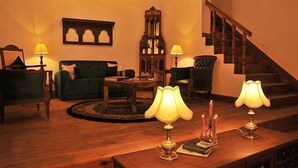 A cozy living room with a sofa, a coffee table, and two lamps on a wooden table. - Te Aroha Dhanachuli (Dhari)