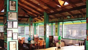A room with wooden beams, green walls, and framed pictures. There are wooden chairs and a table with a green lamp. - Te Aroha Dhanachuli (Dhari)
