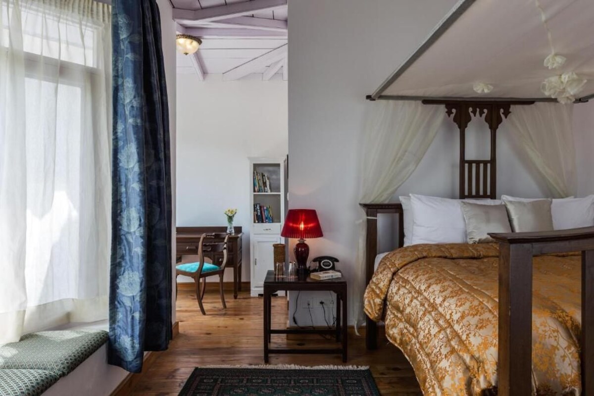 A bedroom with a bed, bedside table, lamp, and a chair.