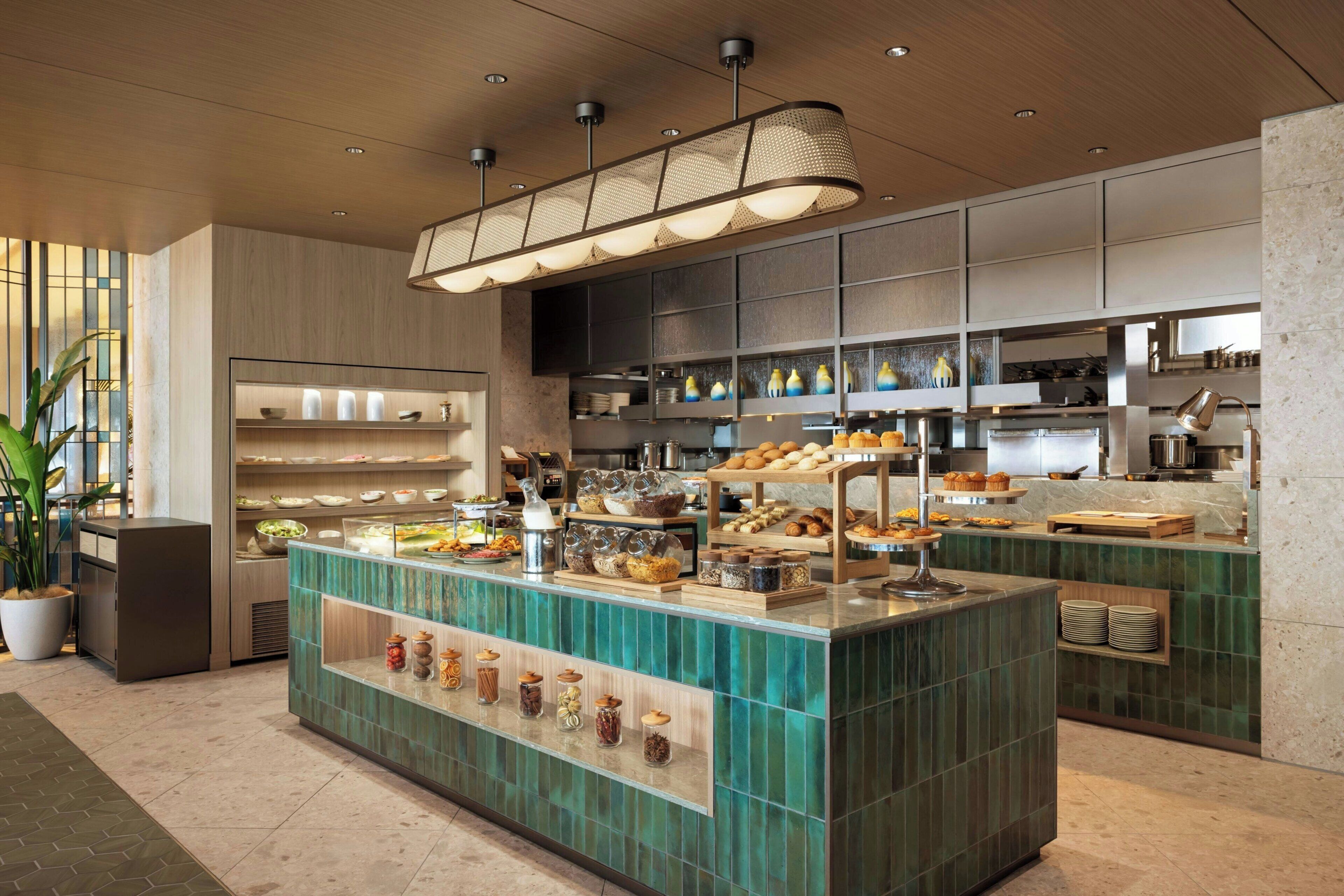 A modern kitchen with a central island, various food items, and a coffee station.