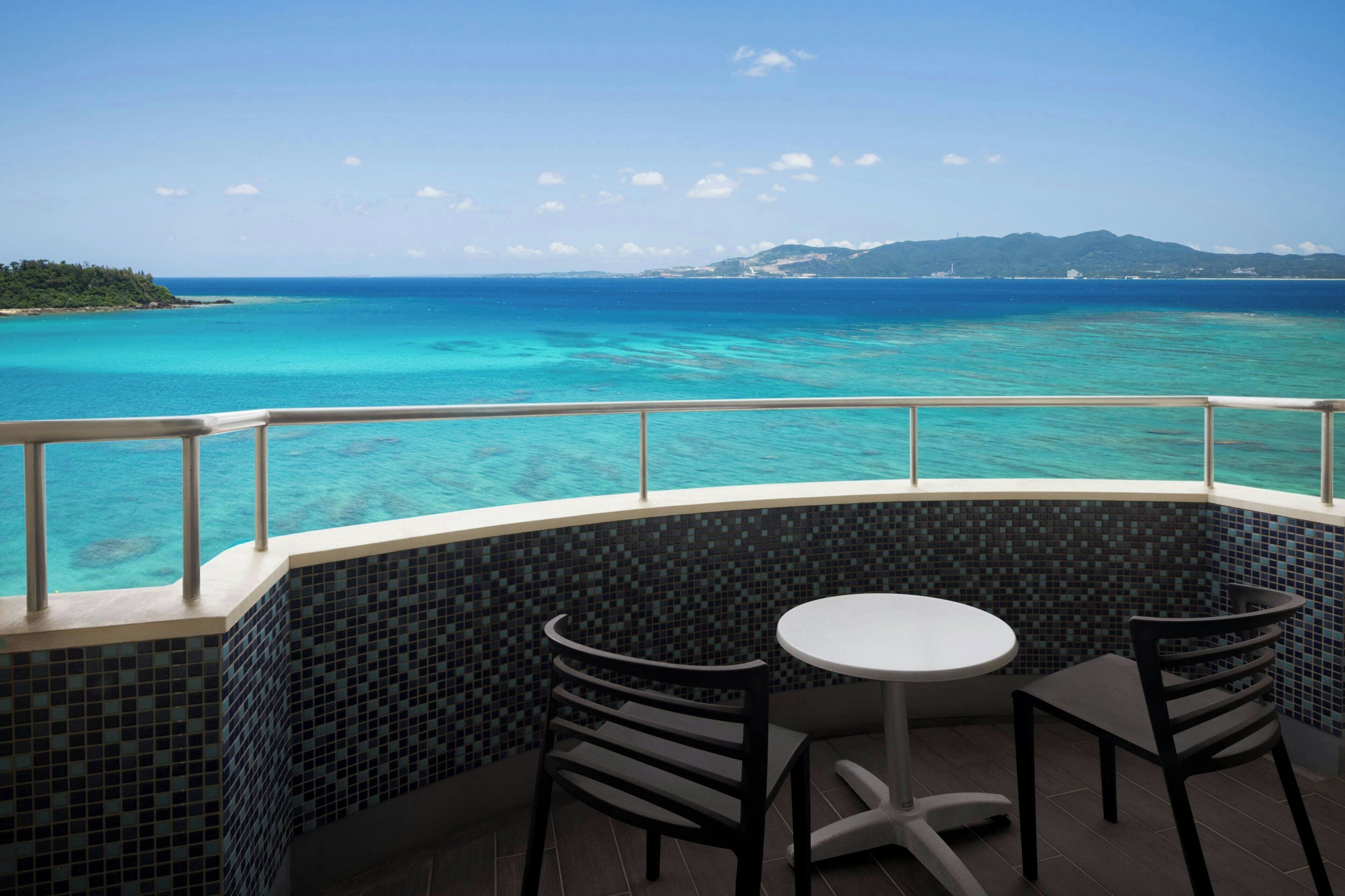 A balcony with a view of the ocean and a tiled wall.